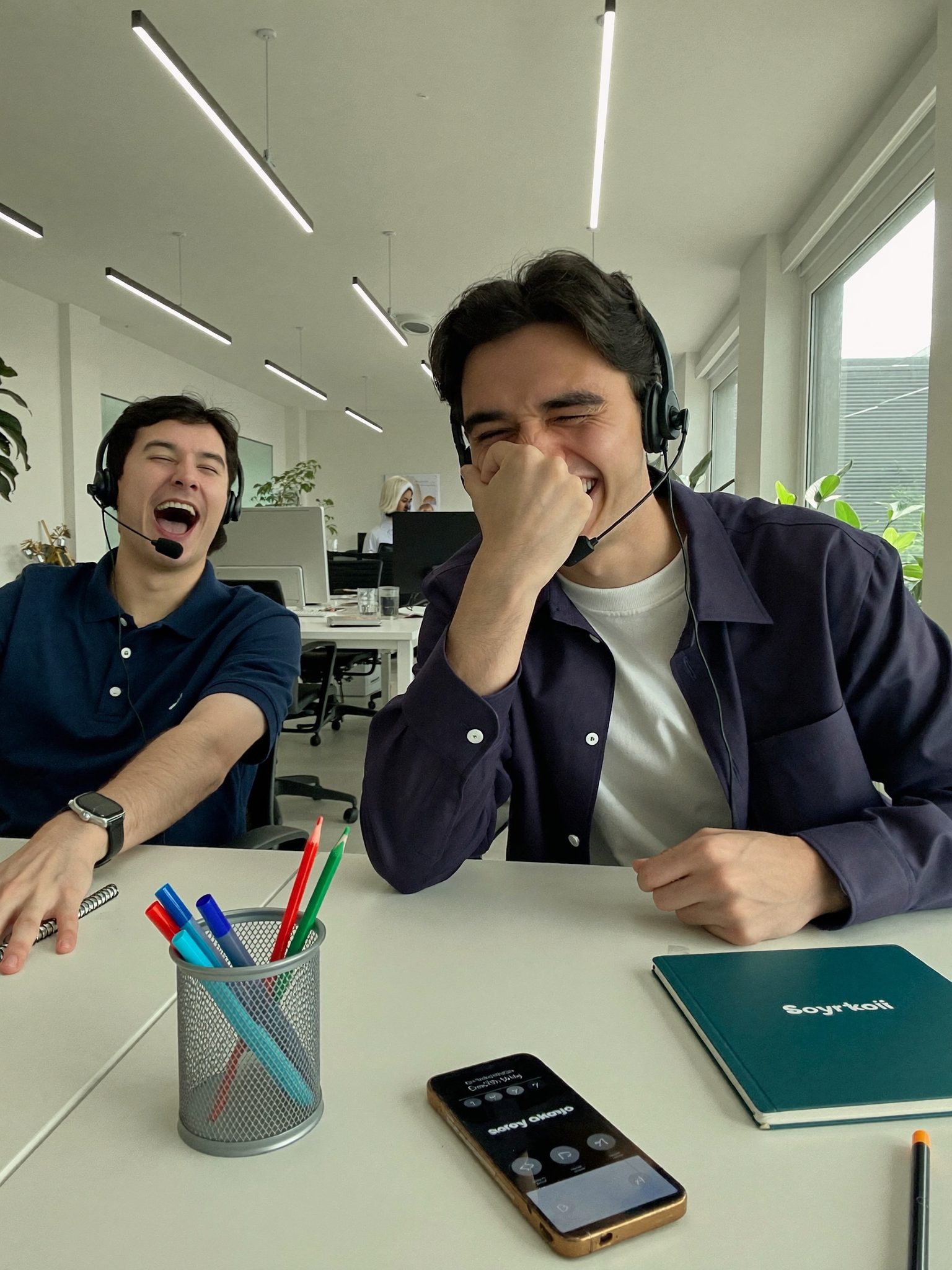 Two reps laughing on headset calls at their desks