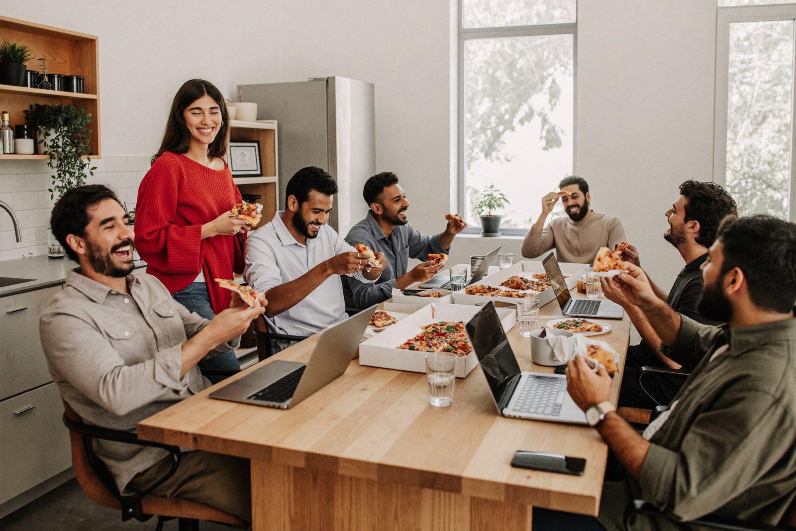 The team sharing pizza at a long table in the office kitchen
